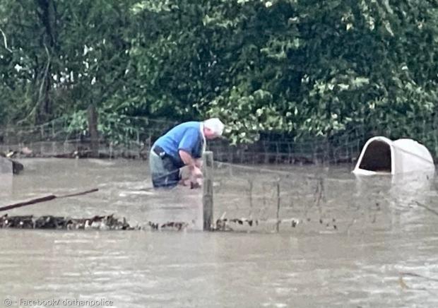 도탄 시 동물관리당국의 빌 뱅크스가 마당에 묶인 채 홍수를 만난 개를 풀어주고 있다. [출처: 도탄 경찰서 페이스북]